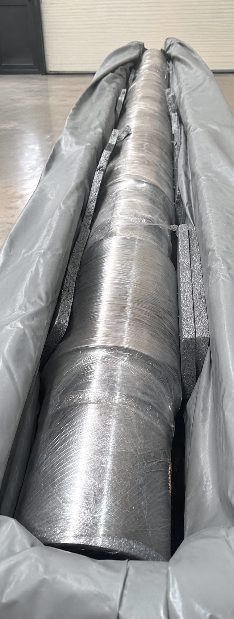 Large machined shaft wrapped and packed in a protective crate