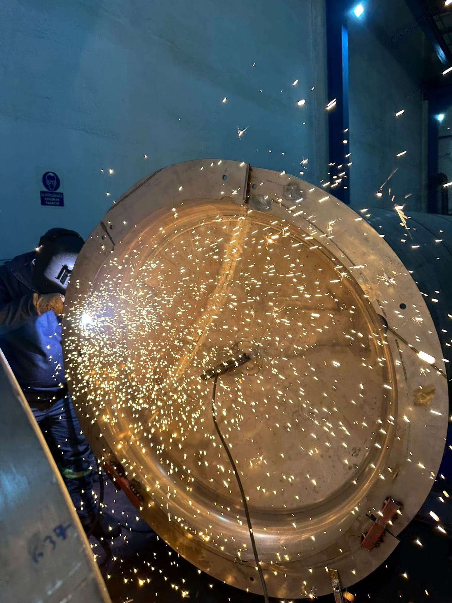 Welder joining the dished head of a stainless steel process vessel